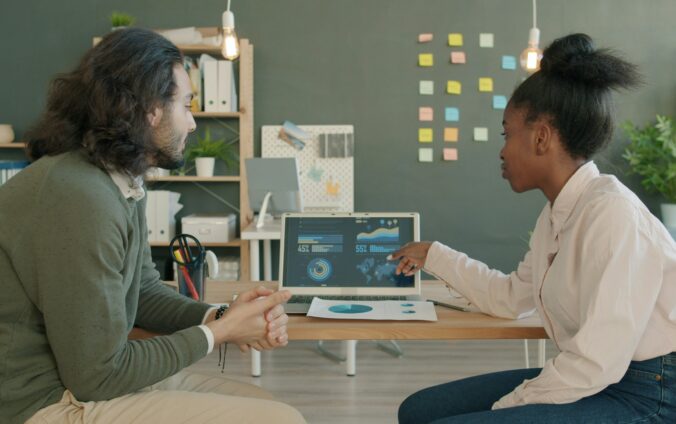 Deux collègues analysent des données sur un ordinateur portable dans un contexte de digitalisation des services